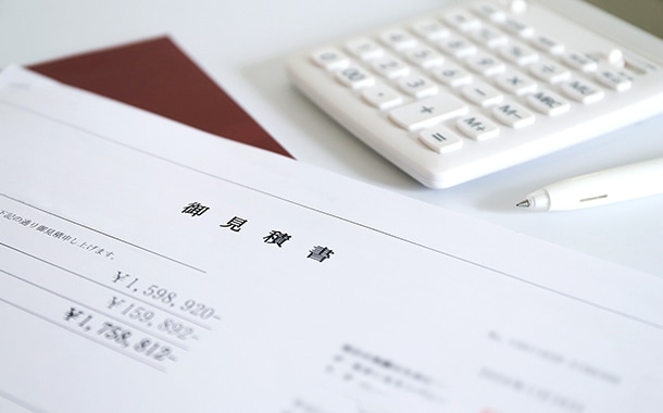 白い机の上に置かれた御見積書。金額欄と電卓、ボールペンが写るビジネス・見積もりのイメージ。